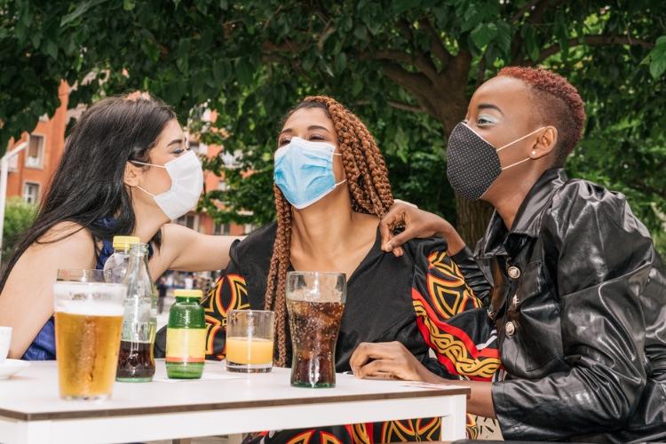 A group of three people wearing masks and drinking beer