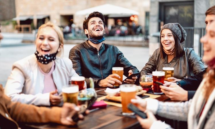 A group of four people laughing, talking and drinking beer